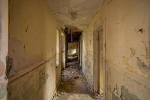 Property for sale A narrow, abandoned hallway with peeling paint and cracked walls hints at the hidden potential of this Scottish manor house for sale. Debris litters the floor, while caved-in ceilings and light from above reveal a unique development opportunity. Presented by Palace Auctions