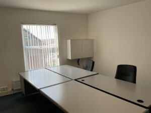 Property for sale A small office with white walls, two black chairs, and four white desks arranged together—an ideal workspace within a Mansfield Road property. Sunlight streams through a window with vertical blinds, and a white wall cupboard sits above the desks. Presented by Palace Auctions