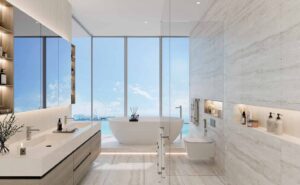 Property for sale Modern bathroom with a freestanding tub, large windows offering a sea view, double sink vanity, glass shower, wall-mounted toilet, and elegant shelving. Bright, minimalist, and luxurious design inspired by LIV LUX at Dubai Marina. Presented by Palace Auctions