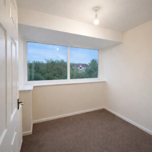 Property for sale A small, empty room with cream-coloured walls, beige carpet, and a large window showing trees and a house outside—ideal for a Hartlepool investment property. A ceiling light is on, and the door is slightly open. Presented by Palace Auctions