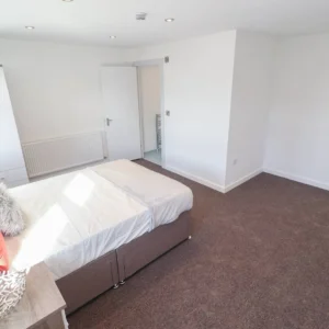 Property for sale A bright, minimal bedroom with a double bed, white bedding, bedside table, white walls, and brown carpet welcomes you. Sunlight pours in as the open door connects the space—an inviting feature of this Coventry PBSA Investment Auction property. Presented by Palace Auctions