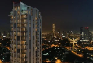 Property for sale A modern high-rise with illuminated balconies rises above the city skyline at night, showcasing the golden eagle logo of "Transcendence Real Estate"—your gateway to Luxury JVC Smart Flats and premium living in Dubai’s Jumeirah Village Circle. Presented by Palace Auctions