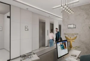 Property for sale Modern office lobby with a reception desk, computer, and paperwork. In the background, two people stand near lift doors. The logo "TRANSPARENCY REAL ESTATE" is on the right wall, reflecting expertise in Luxury JVC Smart Flats. Presented by Palace Auctions