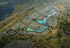 Property for sale Aerial view of the Maldives Cluster at DAMAC Islands, showcasing luxury townhouse living with winding blue water features, green spaces, roads, and numerous homes. Two golden phoenix-like logos are superimposed on the image. Presented by Palace Auctions