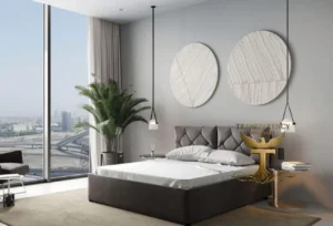 Property for sale A modern bedroom in Luxury JVC Smart Apartments features a large bed, stylish wall art, pendant lights, a potted plant, floor-to-ceiling windows with city views, and a bedside table—ideal for your Dubai investment flat 2026. Presented by Palace Auctions