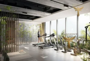 Property for sale A modern gym in a luxury flat at Jumeirah Village Triangle, featuring floor-to-ceiling windows, running machines, exercise bikes, lush greenery outside, potted plants inside, and natural light flooding the spacious room. Presented by Palace Auctions