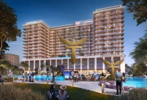 Property for sale A modern multi-storey resort building with balconies is lit up at dusk. People gather around a large swimming pool with palm trees and greenery at DAMAC Riverside Views. The logo for "Transparency" with an eagle is overlaid on the image. Presented by Palace Auctions