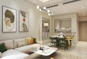 Property for sale Modern living room of a 1-Bedroom Waterfront Apartment at DAMAC Riverside Views, featuring a beige corner sofa, green and yellow cushions, abstract art, marble coffee table, dining area with green chairs, and elegant contemporary lighting in Dubai Investment Park 2. Presented by Palace Auctions
