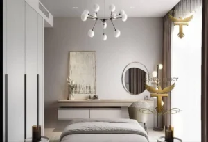 Property for sale A modern, minimalist bedroom in a luxury flat in Jumeirah Village Triangle, Dubai. Neutral tones, a wall-mounted desk with round mirror, abstract art, and stylish lighting create a serene space flooded with natural light from large windows. Presented by Palace Auctions