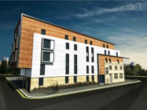 Property for sale Modern multi-storey building with white and wood-toned panels, attached to an older stone structure on the corner of Wakefield Road in Huddersfield, offering contemporary student accommodation under a blue sky with yellow road markings. Presented by Palace Auctions
