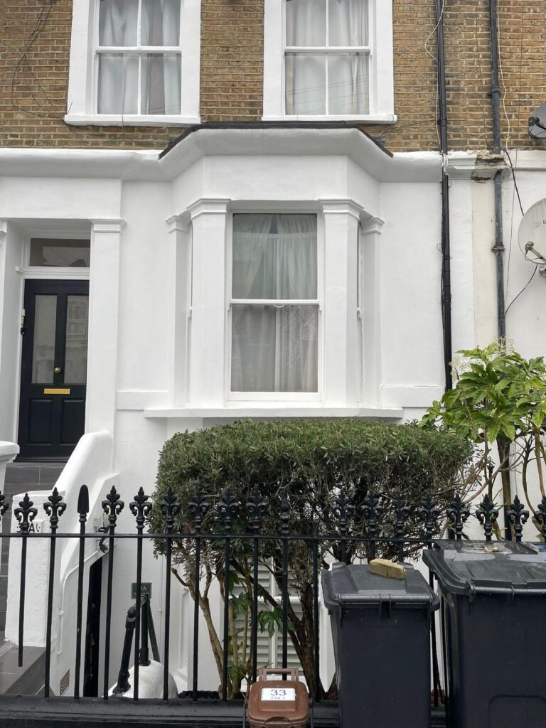 Property for sale A white Poets' Corner ground floor flat with a bay window and black iron railings in front. Two rubbish bins and a brown house number plaque are by the gate; a trimmed hedge and green plant grow in front of the window. Presented by Palace Auctions