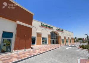 Property for sale A modern Choithrams supermarket building with a beige and brown facade stands near DAMAC Riverside, featuring a large glass entrance and clear blue sky above. Bilingual signage in English and Arabic is visible above the entrance. Presented by Palace Auctions