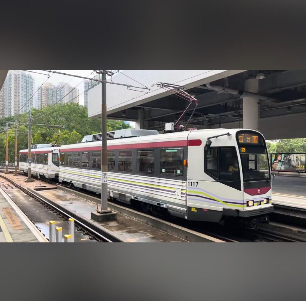 Property for sale A modern light rail train with white, maroon, and grey colours is stopped at an outdoor urban platform near high-rise buildings and greenery—close to where Tuen Mun residential property auctions like a Tuen Mun flat for sale may be found. Presented by Palace Auctions