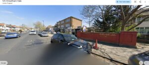 Property for sale A street view of 125 Streatham Vale, Lambeth, London, showing parked cars, a red brick wall with graffiti, a tree, and shops with flats above on a sunny day. Presented by Palace Auctions
