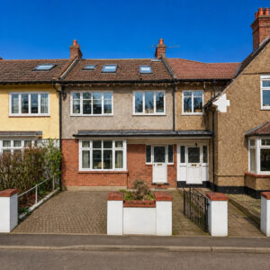 Property for sale A two-storey terraced London family home for sale with a brick and pebbledash exterior, white-framed windows, skylights, and a paved drive, nestled between similar houses under a clear blue sky. Presented by Palace Auctions