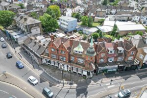 Property for sale Aerial view of a red-brick building with a domed roof on a street corner, surrounded by cars, trees, and residential houses in an urban neighbourhood—a prime Croydon Mixed Use investment property opportunity. Presented by Palace Auctions