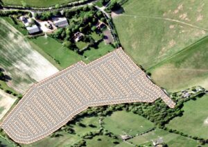 Property for sale Aerial view of rural land with a proposed housing development plan overlaid on green fields, highlighting freehold plots Surrey near Washpond Lane land, surrounded by farmland and scattered houses. Presented by Palace Auctions